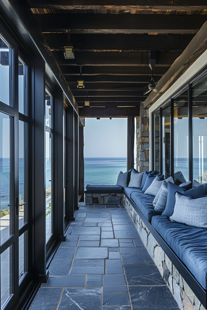 African coastal enclosed long porch, narrow corridor perspective, black wood beams and matte black window framing, ash gray stone flooring, deep blue linen cushions on built-in bench seating, ocean visible through glass panels, soft diffused natural light, minimal decor, sacred geometry subtle patterns etched into surfaces, calm grounded atmosphere, architectural precision, no clutter, modern African coastal design, high-end editorial, serene and structured,
